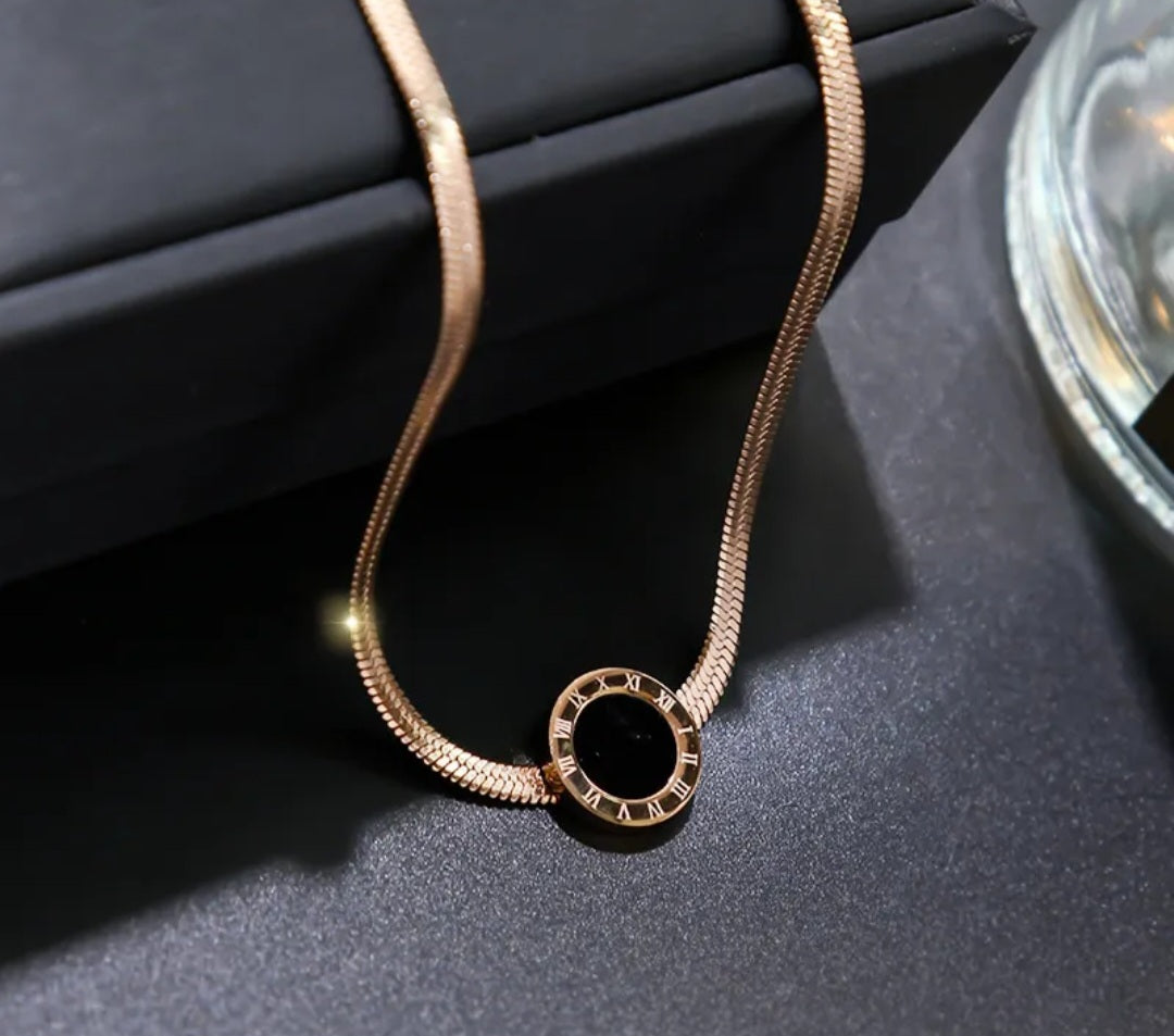 NIDA charm necklace featuring an intricate pendant design on a sleek chain against a dark background.