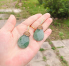Amy Drop Earrings showcasing rhinestone-studded green crystal pendants in a hand, perfect for adding glamour.