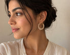 Chunky pearl hoop earrings worn by a model, showcasing 18k gold plating and white pearls, perfect for stylish outfits.