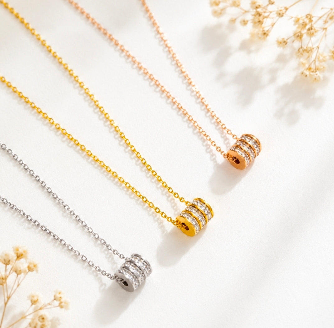 Cubic zirconia pendant necklace collection featuring sleek cylindrical designs in silver, gold, and rose gold styles.