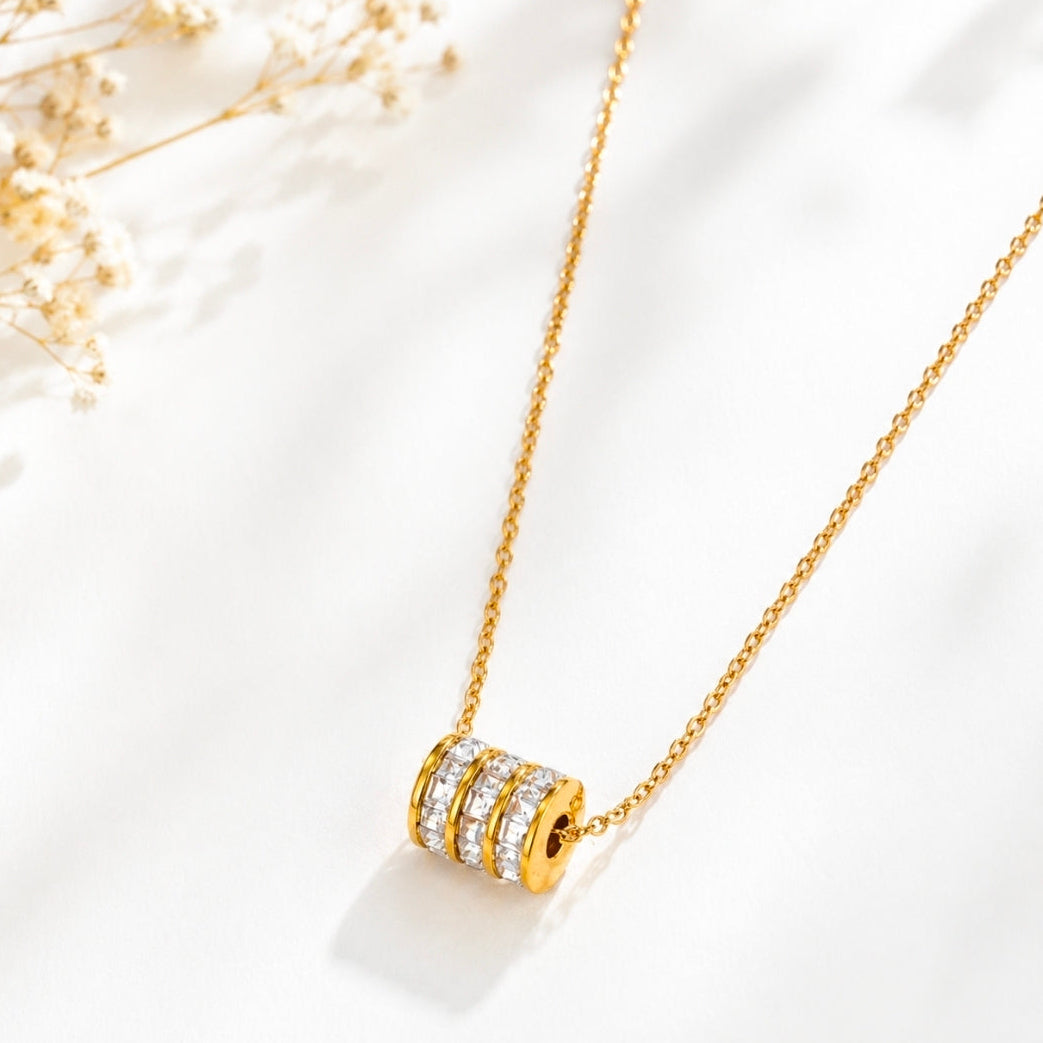 cubic zirconia pendant necklace featuring a sleek cylindrical design with shimmering stones on a gold chain.